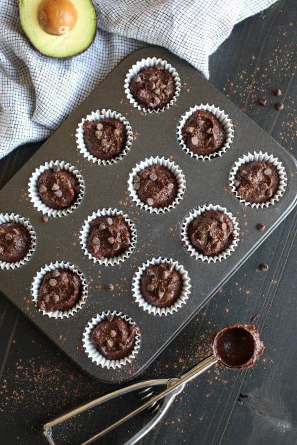 Overhead view of a mini muffin pan filled with Paleo Double Chocolate Beet Brownie batter with a cookie scoop lying next to the pan.