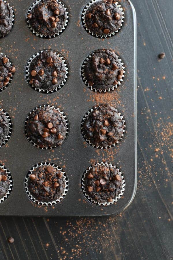 Pan of Paleo Double Chocolate Beet Brownies out of the oven on a black wooden table top dusted with cocoa powder.