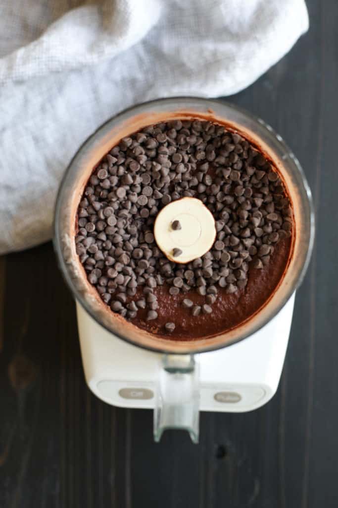 Overhead view of a food processor filled with Paleo Double Chocolate Beet Brownie batter and chocolate chips on top