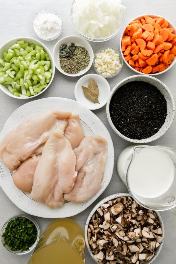 Uncooked wild rice in bowl next to more ingredients for chicken wild rice soup