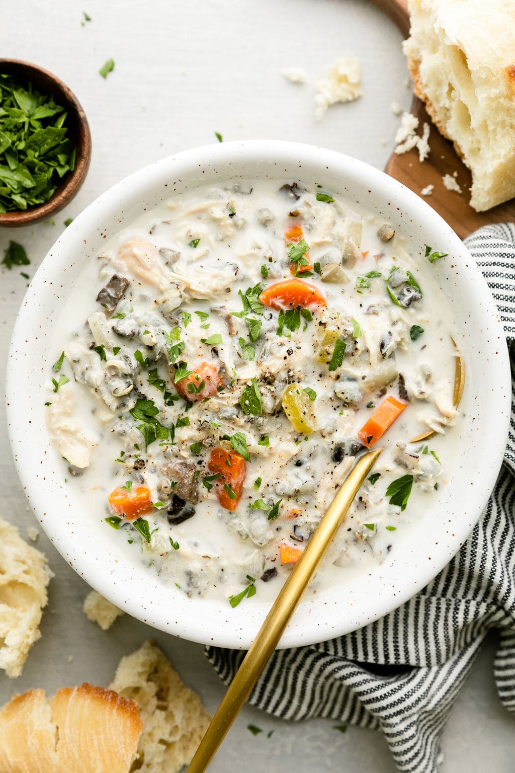 Overhead view creamy chicken wild rice soup in a bowl with gold cutlery.