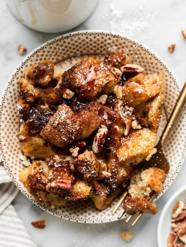 Overhead view serving of crockpot French toast casserole on plate topped with maple syrup and pecans