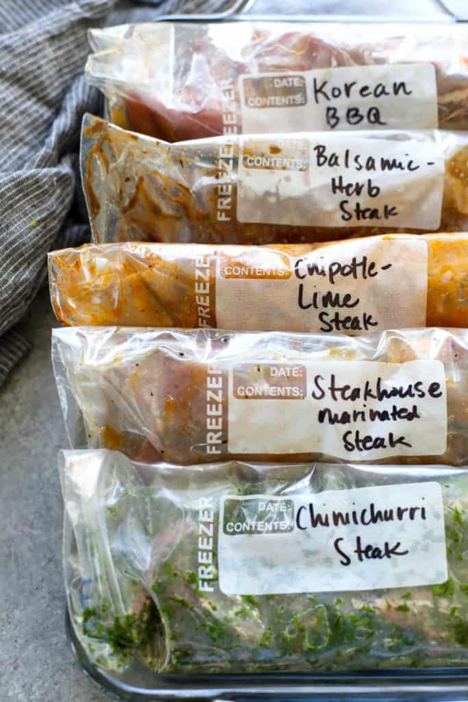 5 zip-top plastic bags marinated steak contained in a rectangular glass dish