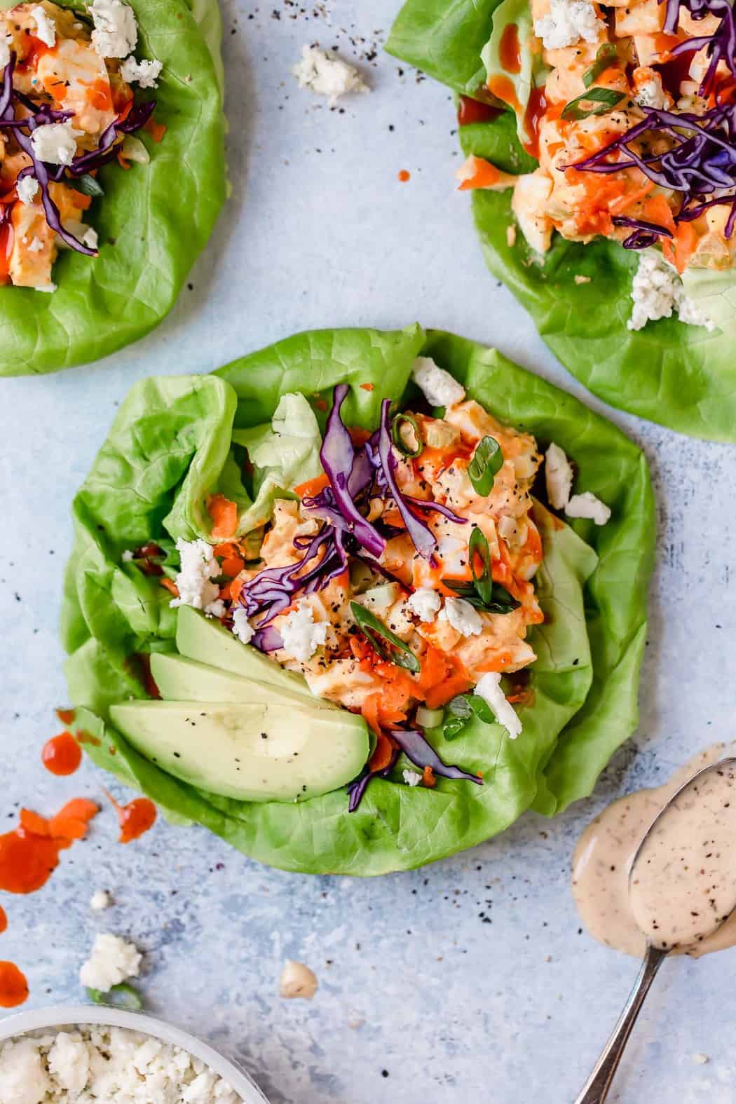 Overhead view of lettuce wraps of buffalo ranch egg salad topped with sliced avocado