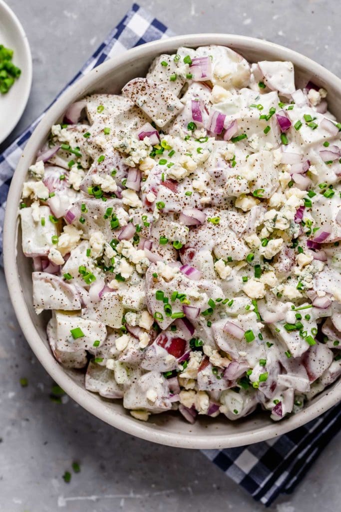 Close up view of a bowl of Blue Cheese Potato Salad with Chives topped with black pepper