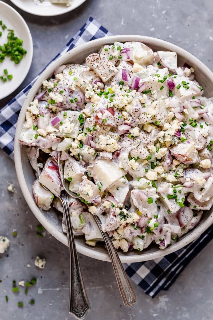 Overhead view of a white bowl filled with Blue Cheese Potato Salad with Chives