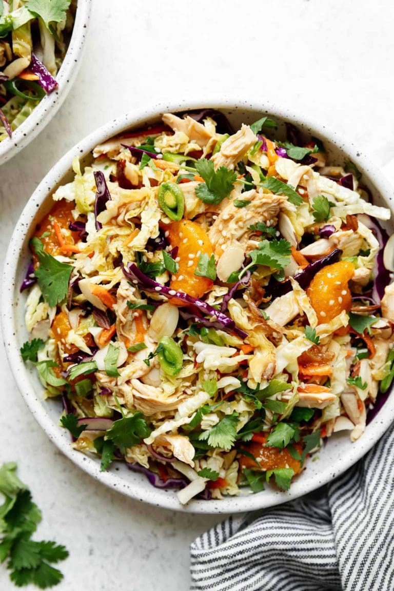 Overhead view of a plate of Chinese-inspired chicken salad topped with sweet oranges and sesame seeds. 