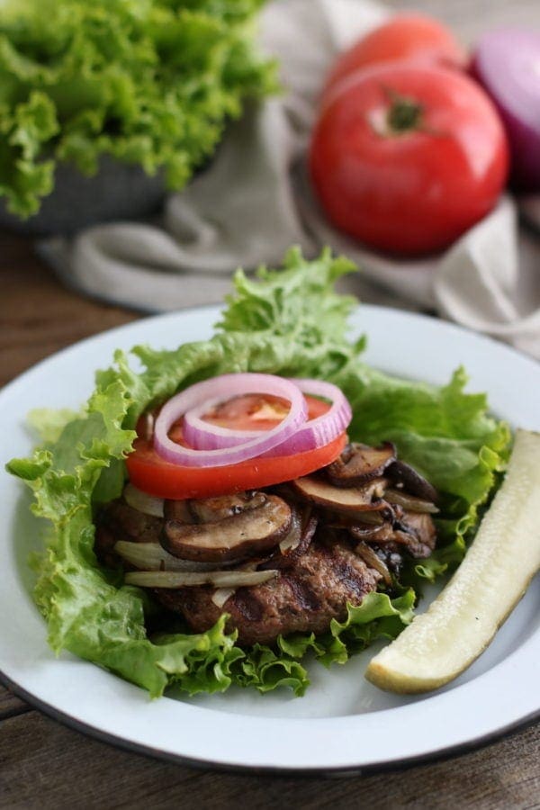 a grilled burger with toppings on a bed of lettuce