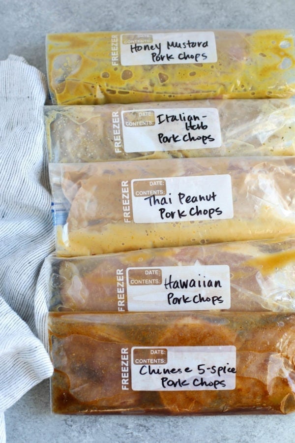 Array of marinated pork chops lying flat on a table in zip-top bags featuring 5 pork marinades 