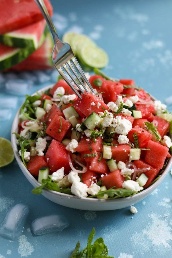 Close up view of a bowl of Watermelon-Cucumber Salad with Feta with a fork going into a piece of watermelon