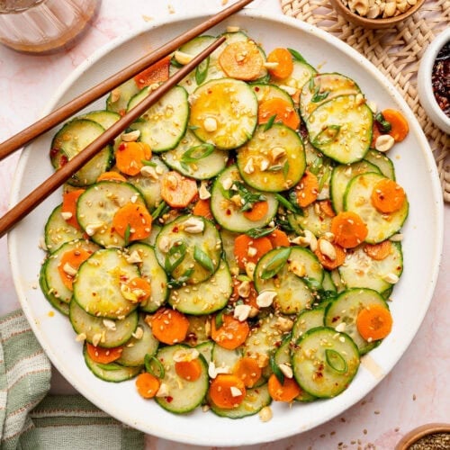 Overhead view of a large bowl filled with Asian Cucumber Salad topped with chili crunch sauce.