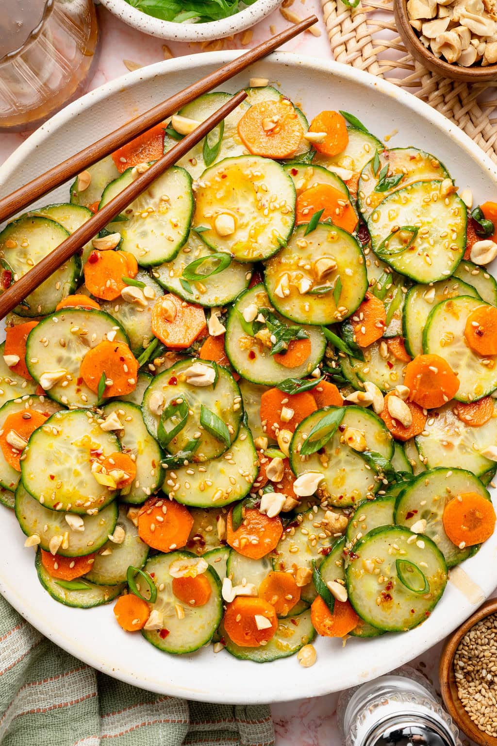 Overhead view of a bowl of Asian Cucumber Salad topped with crushed peanut pieces and green onions. 