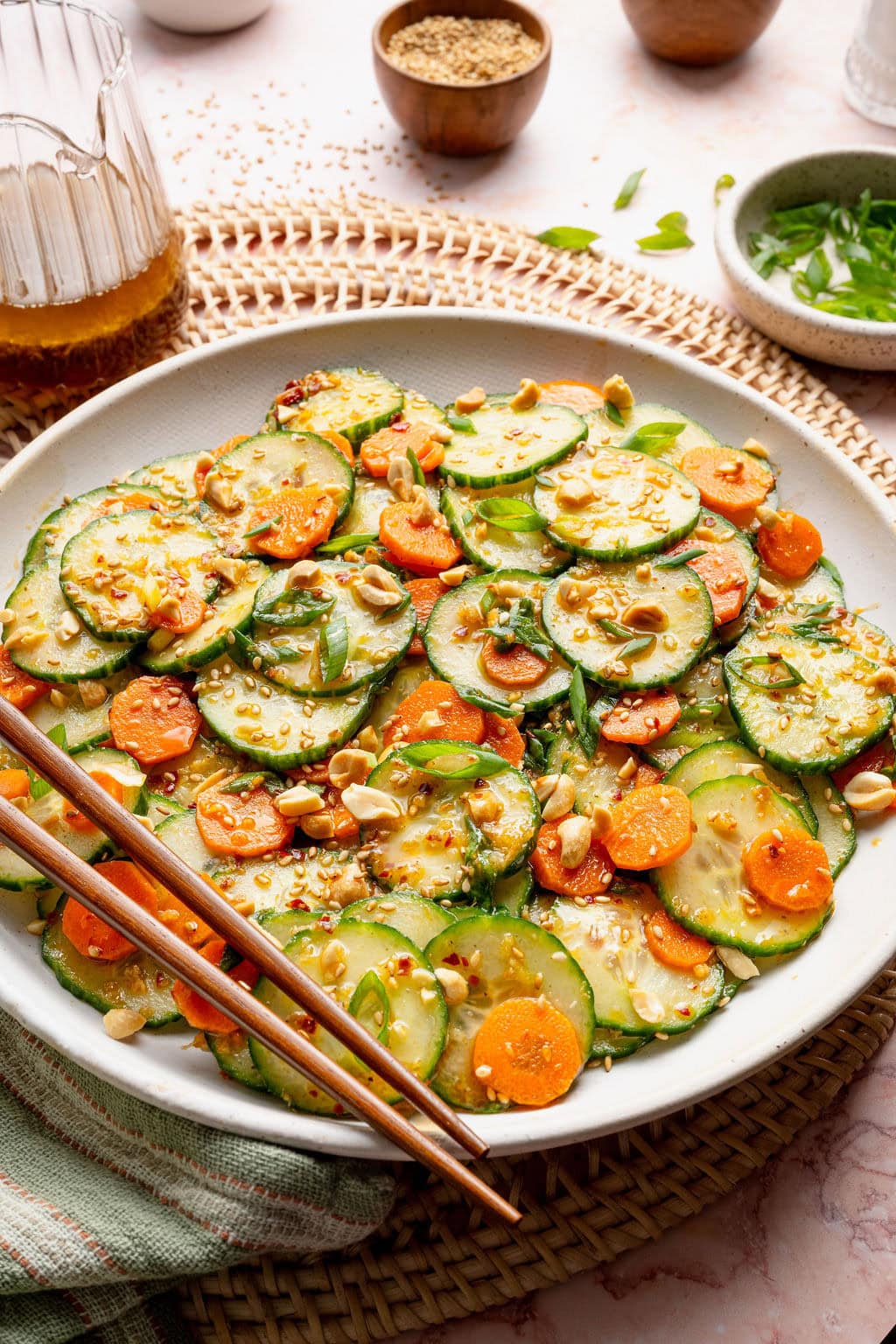 Close up view of a plate filled with Asian Cucumber Salad topped with sesame seeds, peanut pieces, and green onions.