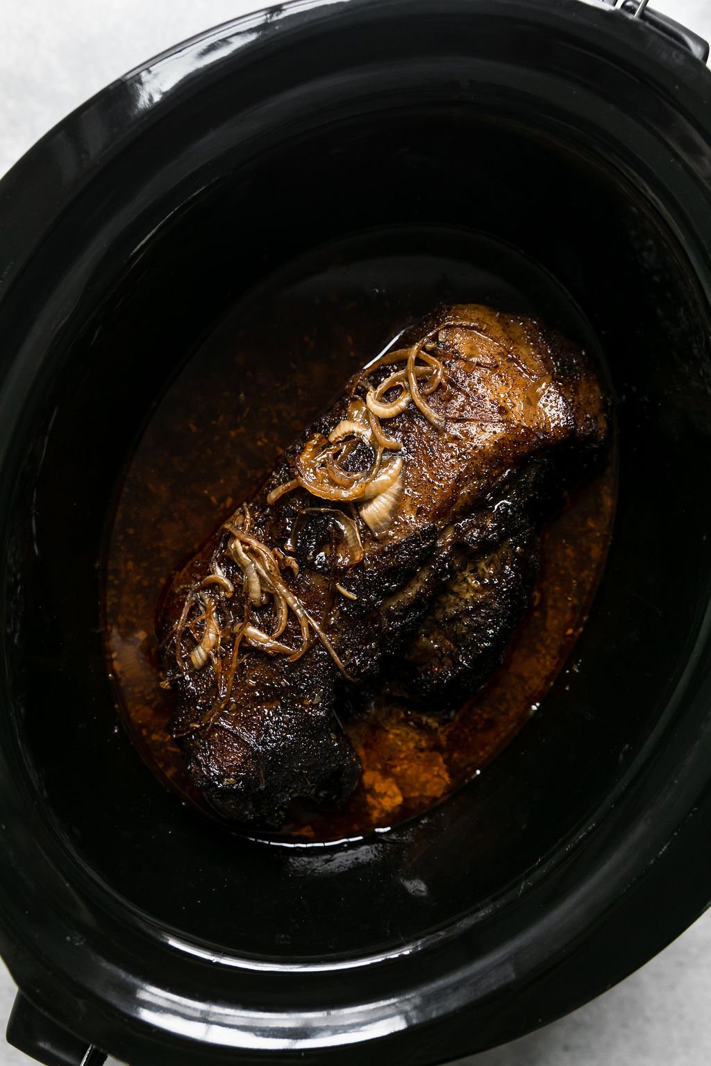 Overhead view of slow cooker carnitas in a black crockpot 
