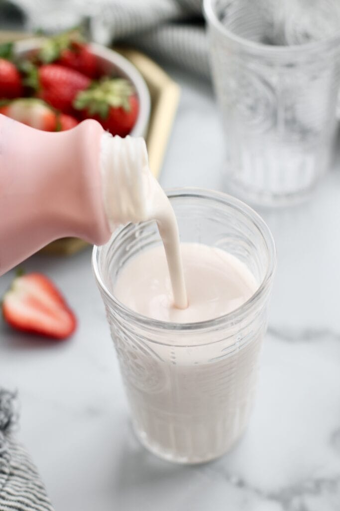 Close up view of strawberry kefir being poured into a glass.
