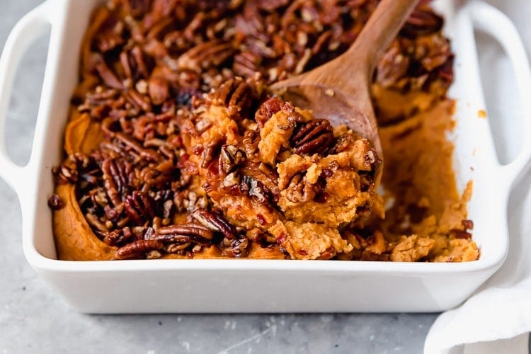 Close up view sweet potato casserole with pecans in white casserole dish