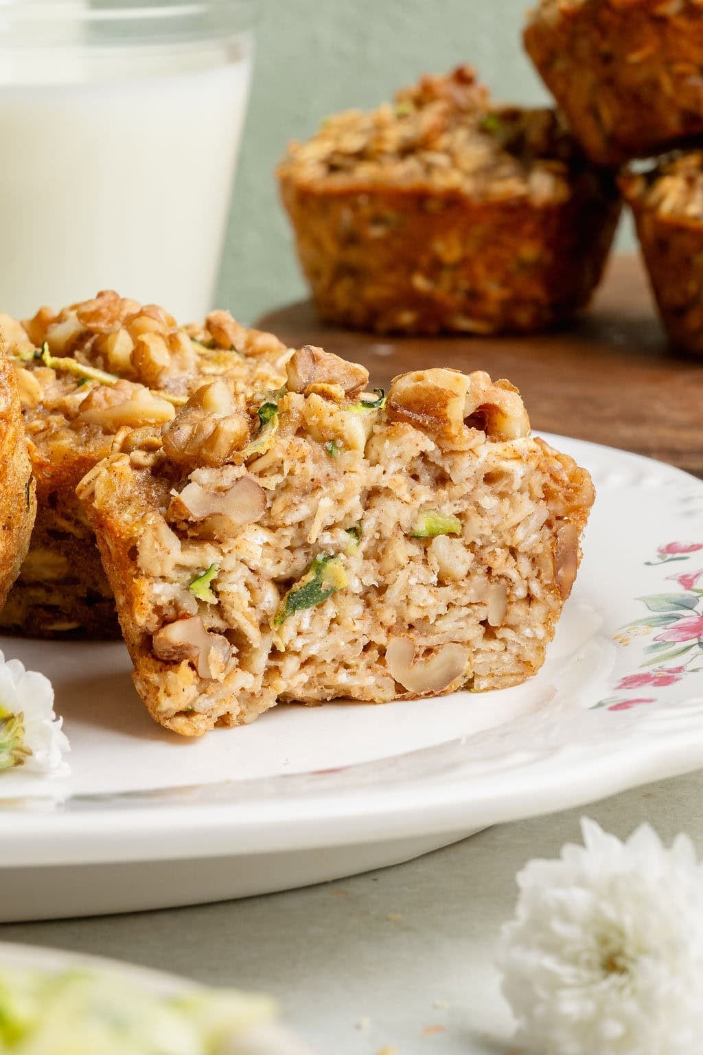 A plate of breakfast oatmeal cups, the front cup split in half exposing shreds of zucchini.