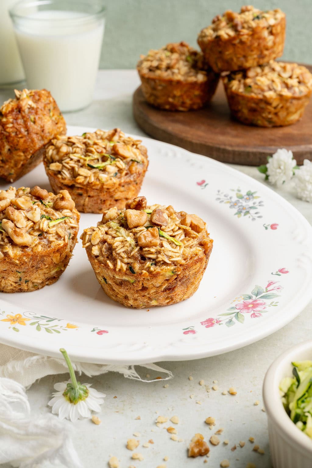 A plate of baked oatmeal cups with three stacked oatmeal cups and a glass of milk behind it.