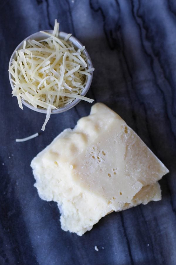Overhead view of a block of cheese and some shredded cheese in a bowl