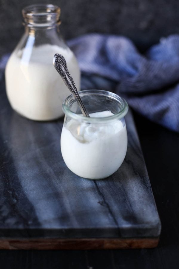 A glass of milk and a glass jar filled with greek yogurt