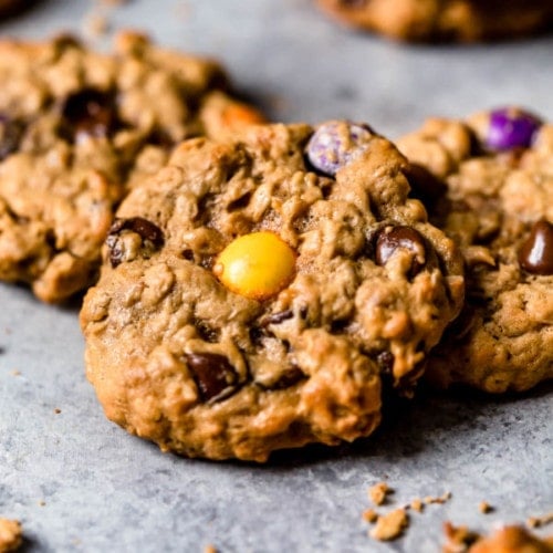 A trio of monster cookies on a grey table.
