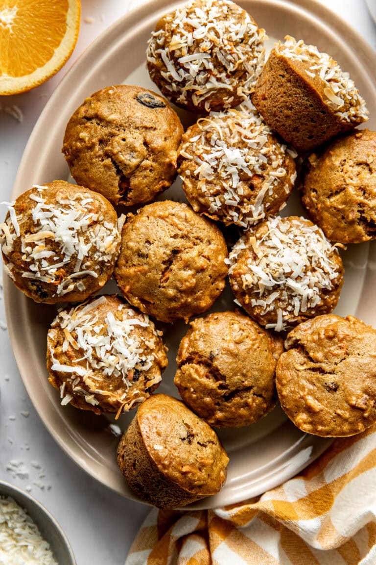 Overhead view of a platter of morning glory muffins, some sprinkled with coconut flakes.