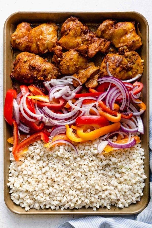 Overhead view of a sheet pan filled with Easy Sheet Pan Chicken Shawarma Bowls with Veggies ingredients