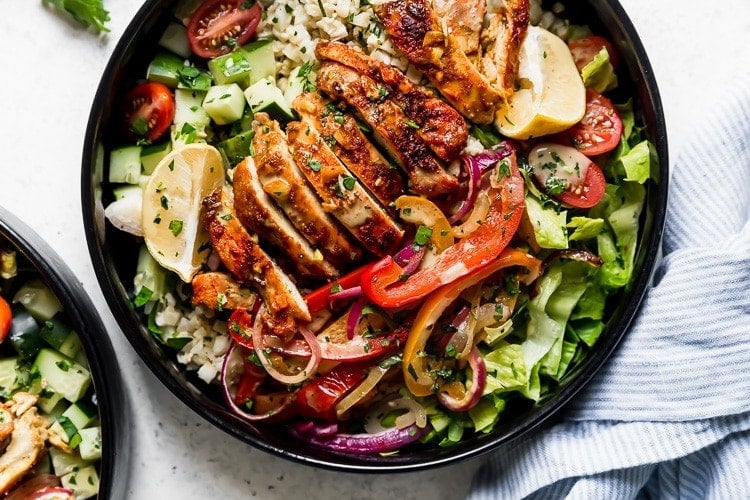 Sheet pan chicken shawarma served in bowl over cauliflower rice and colorful peppers. 