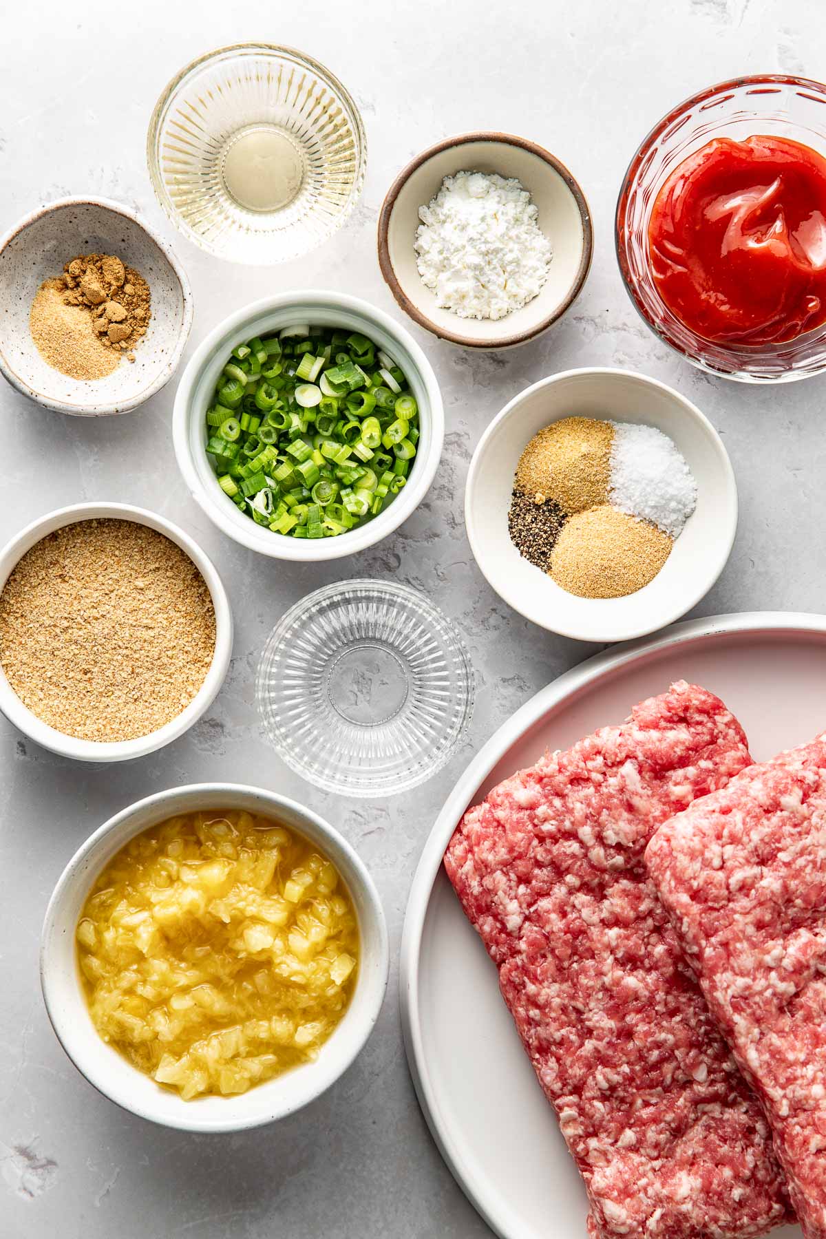 Overhead view of a variety of ingredients for sweet and sour meatballs in different sized bowls.