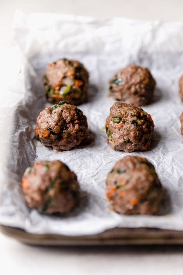 Meal Prep Meatballs in rows on a sheet pan lined with white parchment paper
