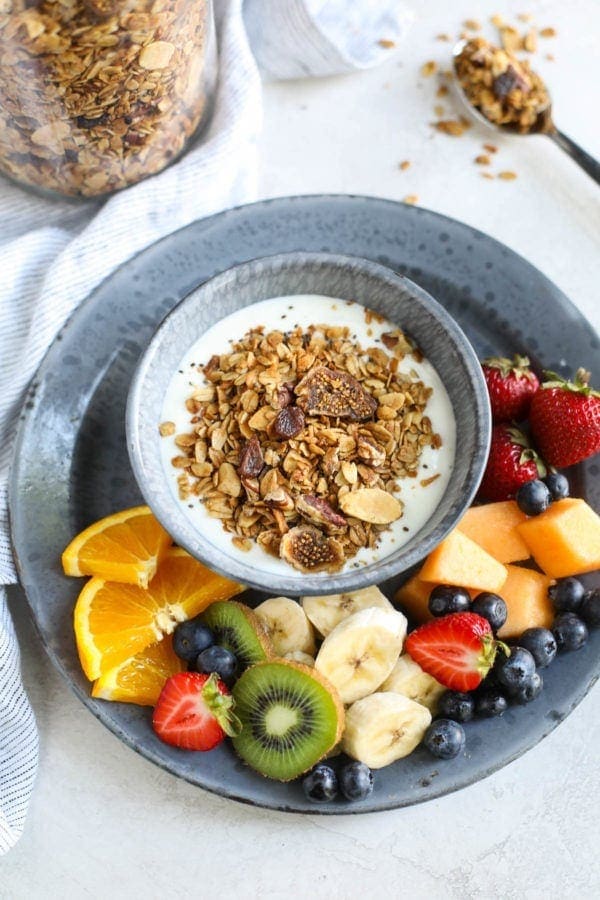 A bowl of Maple Cinnamon Granola surrounded by fresh fruit.