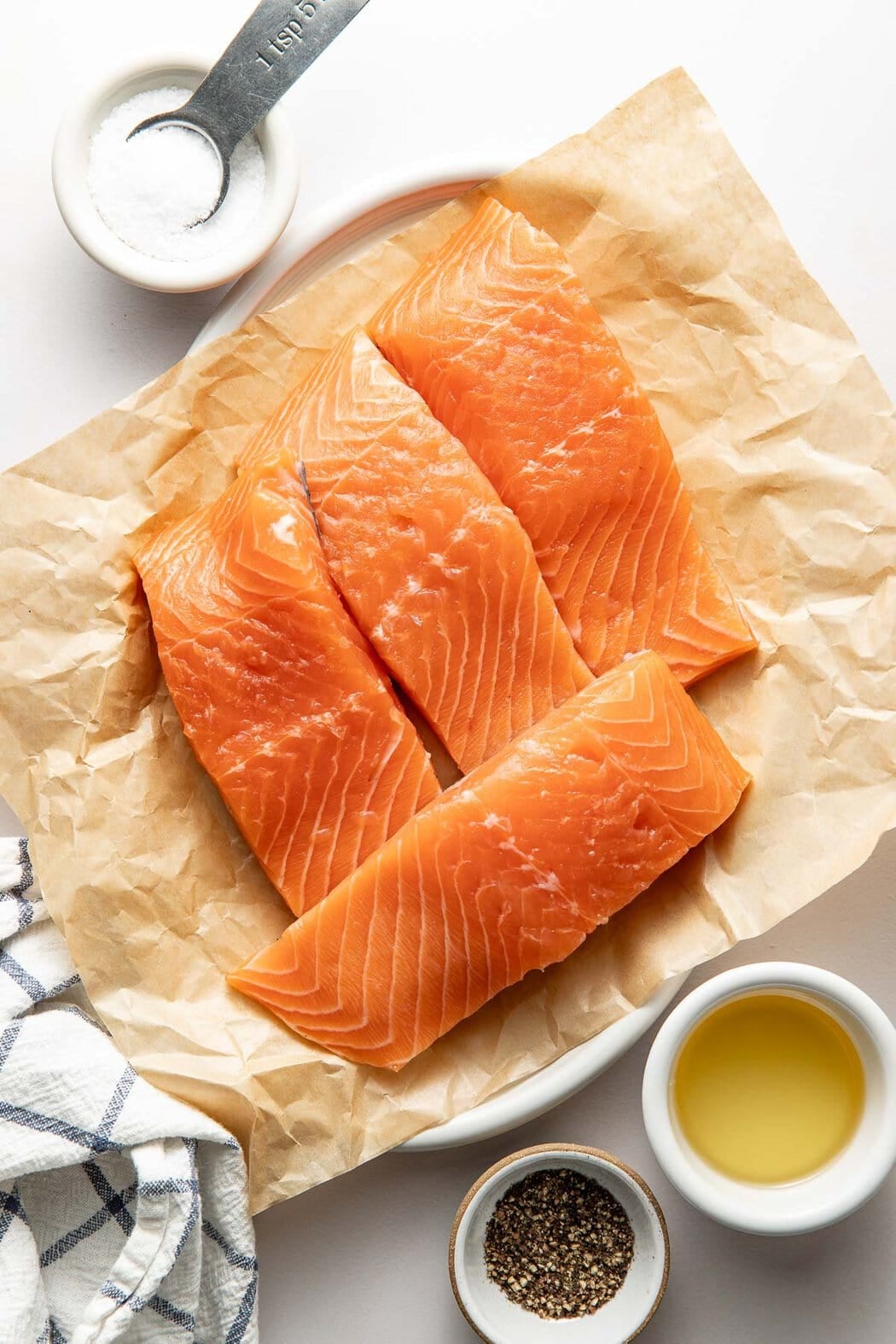 Overhead view of raw salmon fillets on parchment paper.
