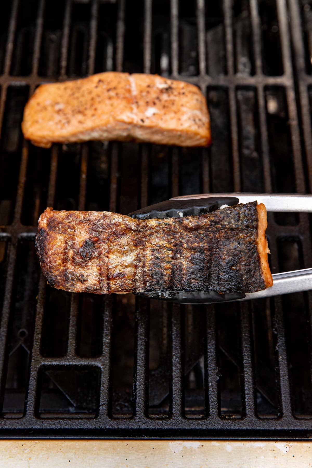 Close up view of a salmon fillet on a grill showing the crisp skin side that was down.