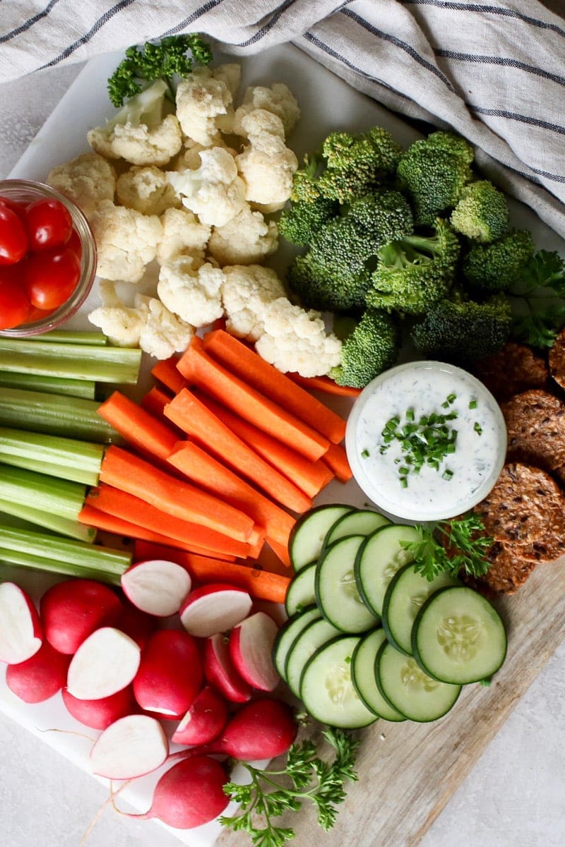 Overhead photo of Healthy Homemade Ranch Dressing in a mason jar topped with fresh chives and surrounded by fresh cut vegetables.
