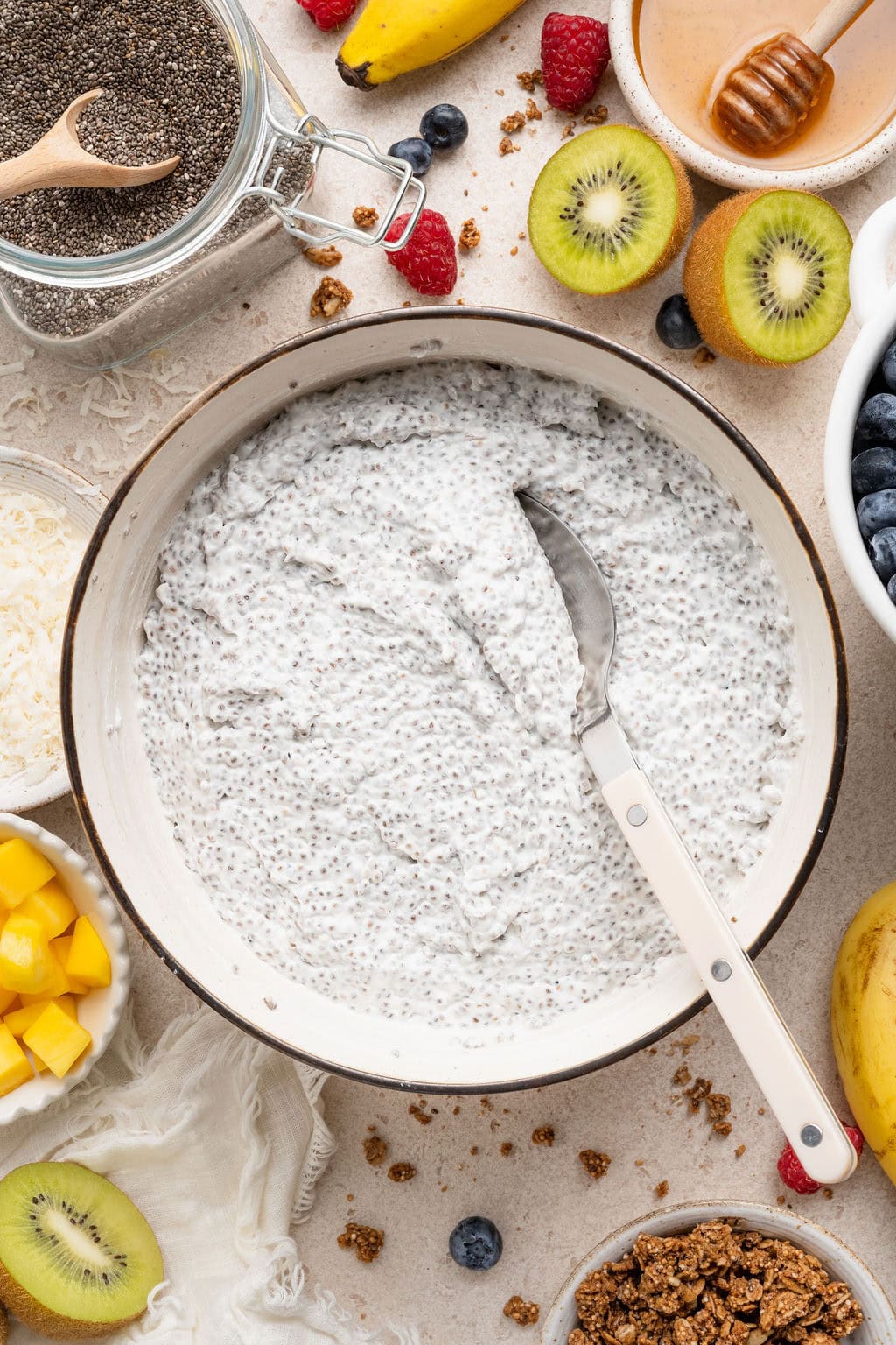 Overhead view of a large white bowl filled with chia pudding and fresh fruit surrounding the outside of the bowl. 