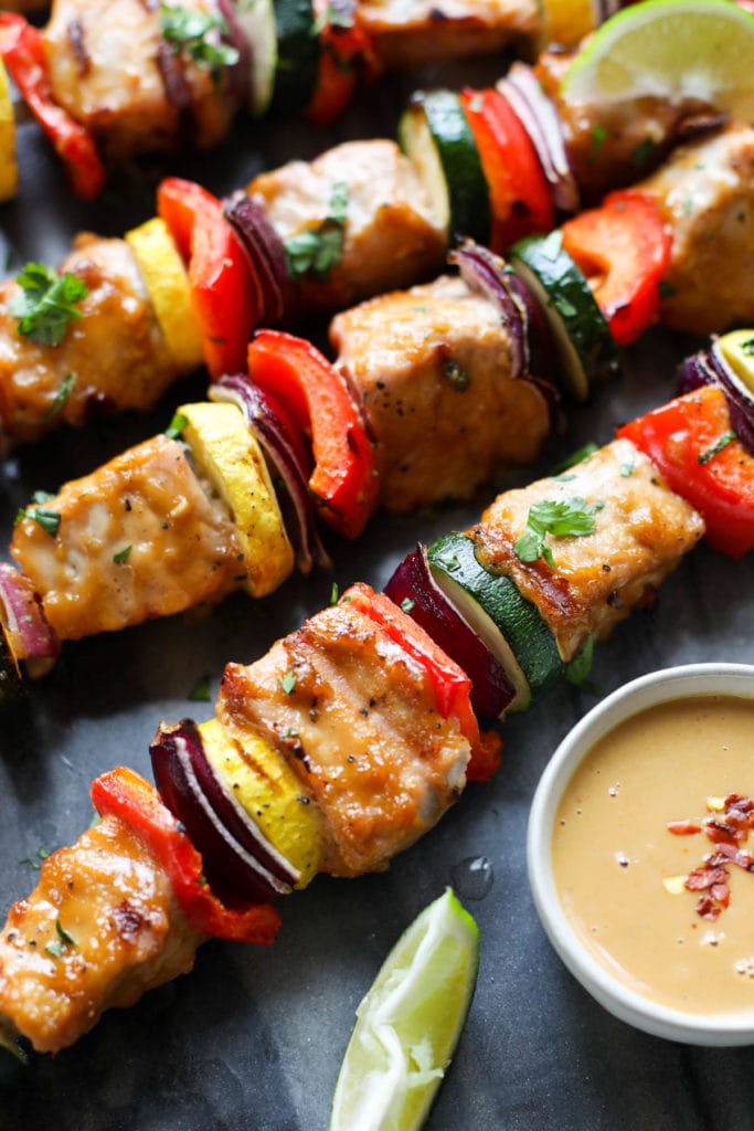 close up view of Grilled Pork Kebabs with Peanut Sauce topped with red pepper flakes