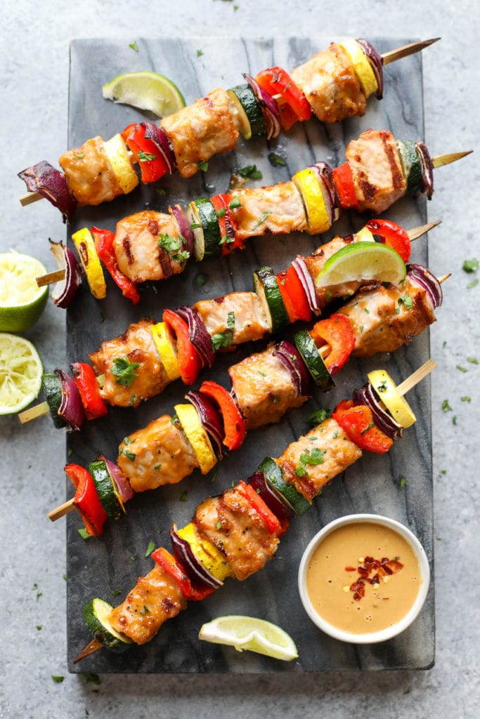 Grilled Pork Kebabs with Peanut Sauce on a marble cutting board