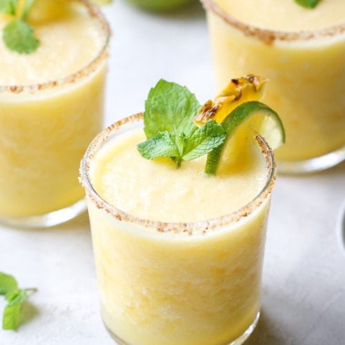 Short glasses filled with frozen pineapple margarita