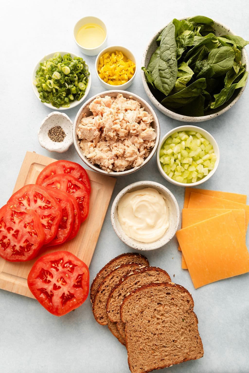 Overhead view of a variety of ingredients for Tuna Melts in different sized bowls.