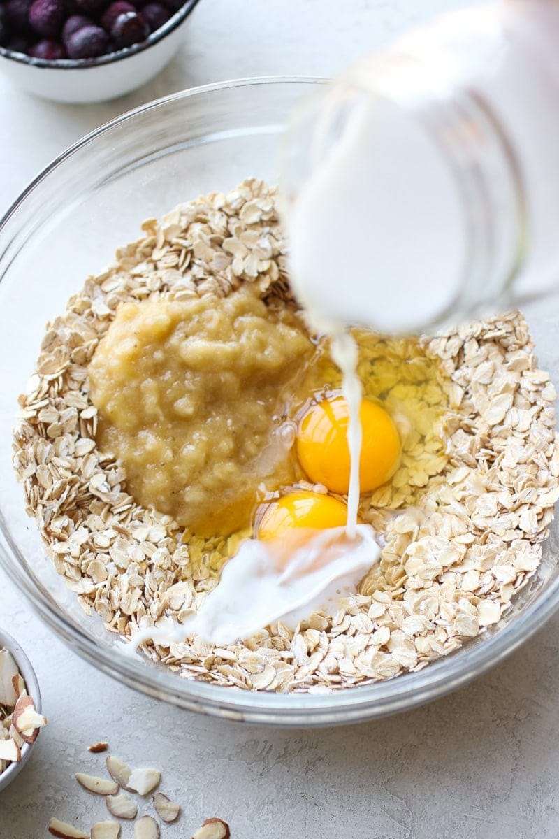 Milk being poured into a mixing bowl for blueberry baked oatmeal