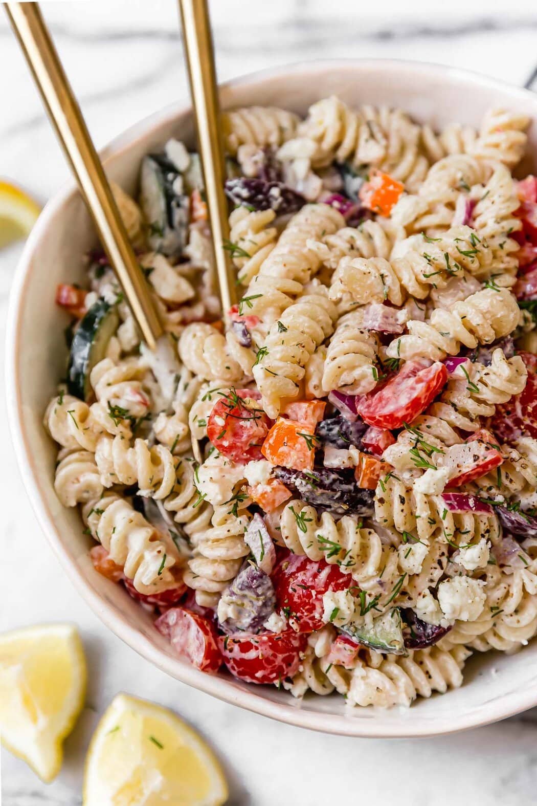Easy Greek Veggie Pasta Salad in a white bowl and topped with fresh dill.