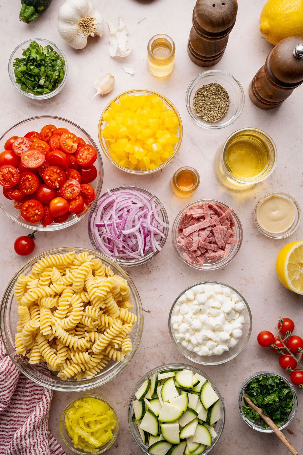 Overhead view of a variety of ingredients for Zesty Italian Pasta Salad in different sized bowls.