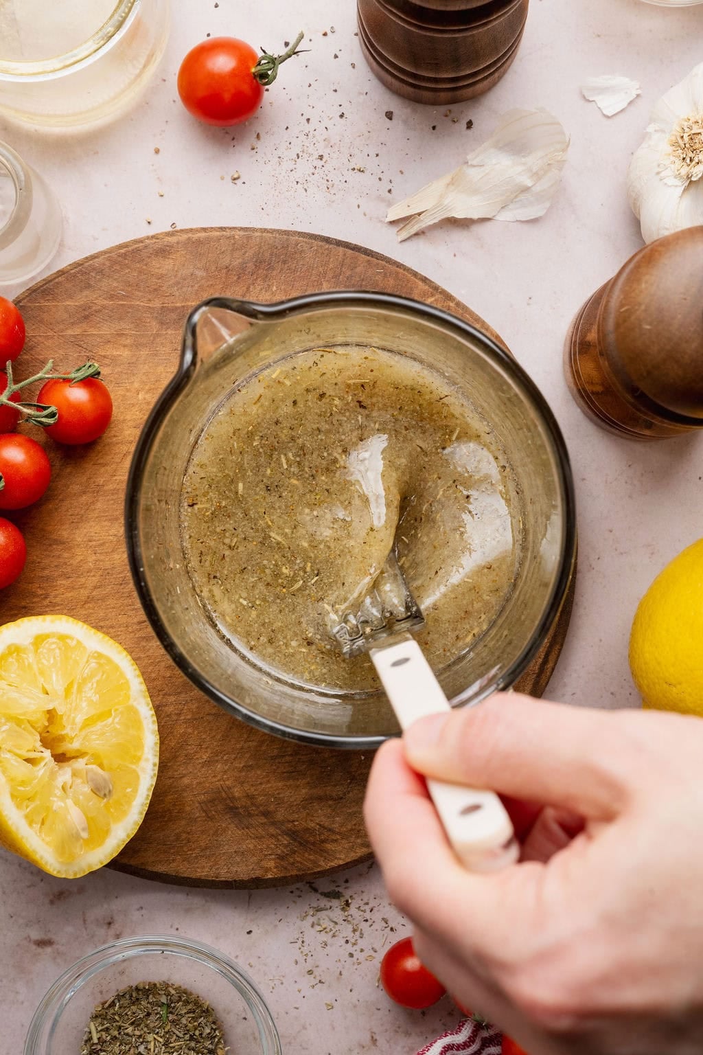 Overhead view of a hand stirring a measuring glass of Italian Dressing.