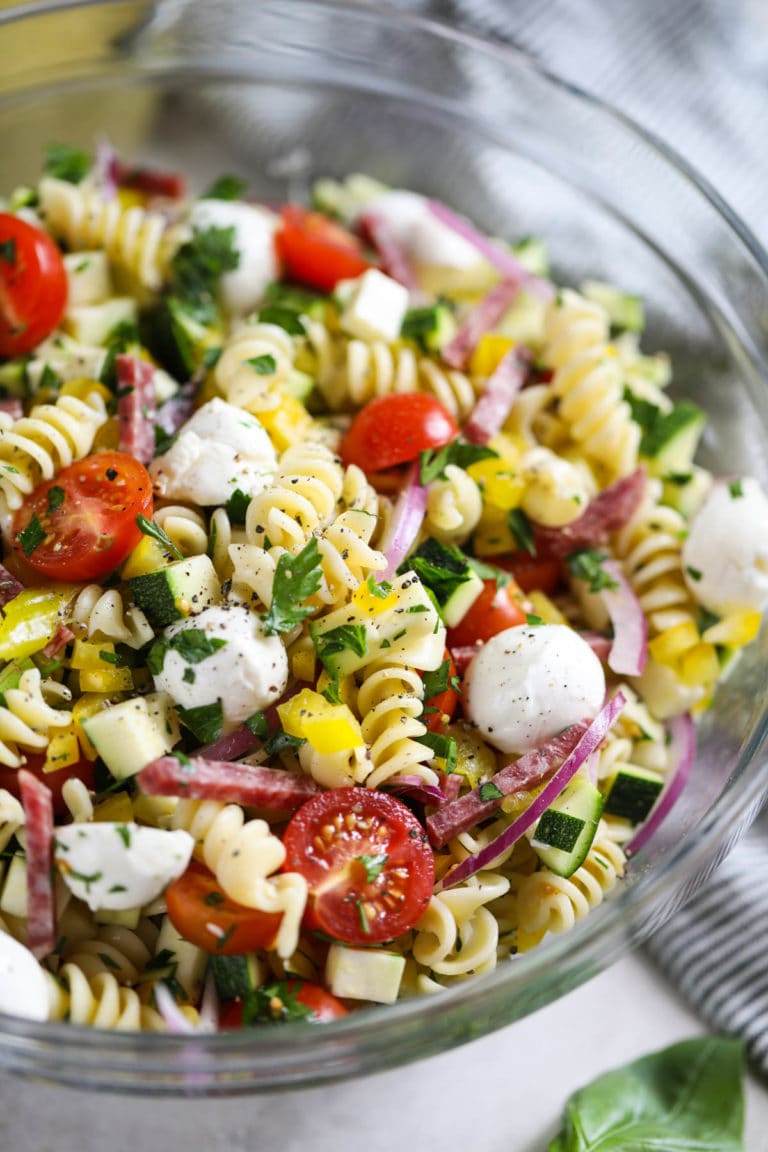 Overhead view of a glass serving bowl filled with colorful zesty Italian Pasta Salad topped with fresh parsley.
