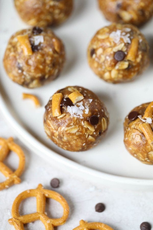 Chocolate chip energy bites with pretzels on a white platter.