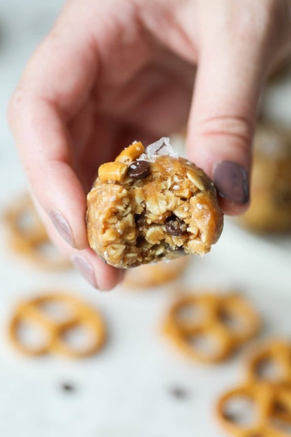 A sweet and salty peanut butter bite with a bite taken out of one side being held by a hand.
