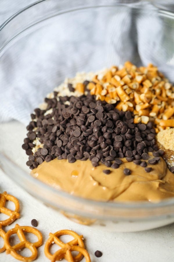 The ingredients for chocolate chip and pretzel no-bake energy bites in a large glass bowl.