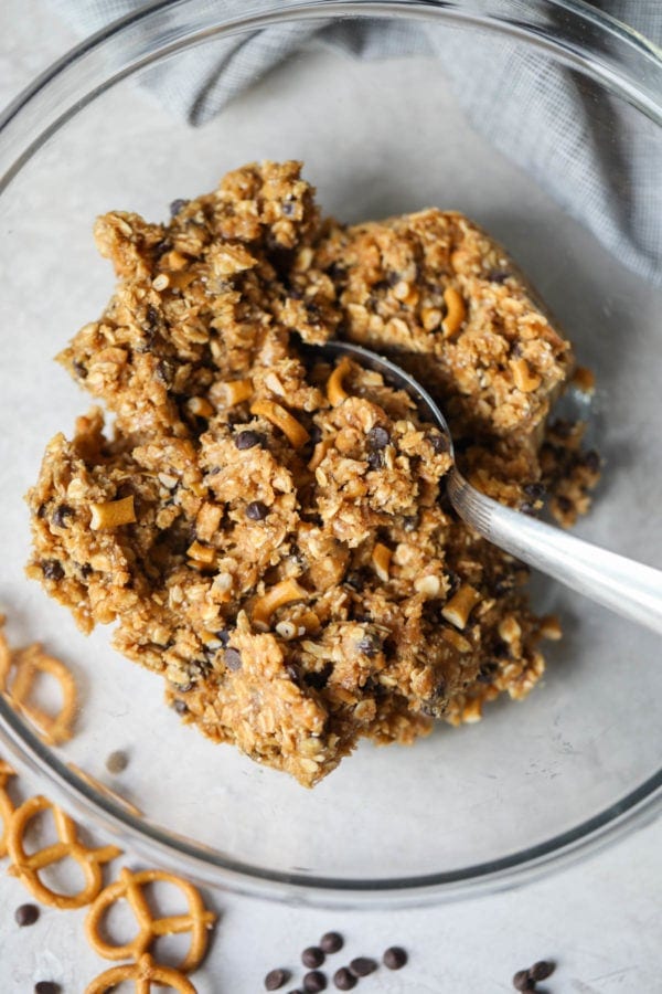 No-bake gluten-free chocolate chip energy bite dough in a glass bowl with a spoon in the middle of the dough.