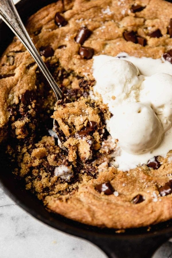 A close up shot of an easy Vegan Chocolate Chip Cookie Skillet topped with vanilla ice cream. 