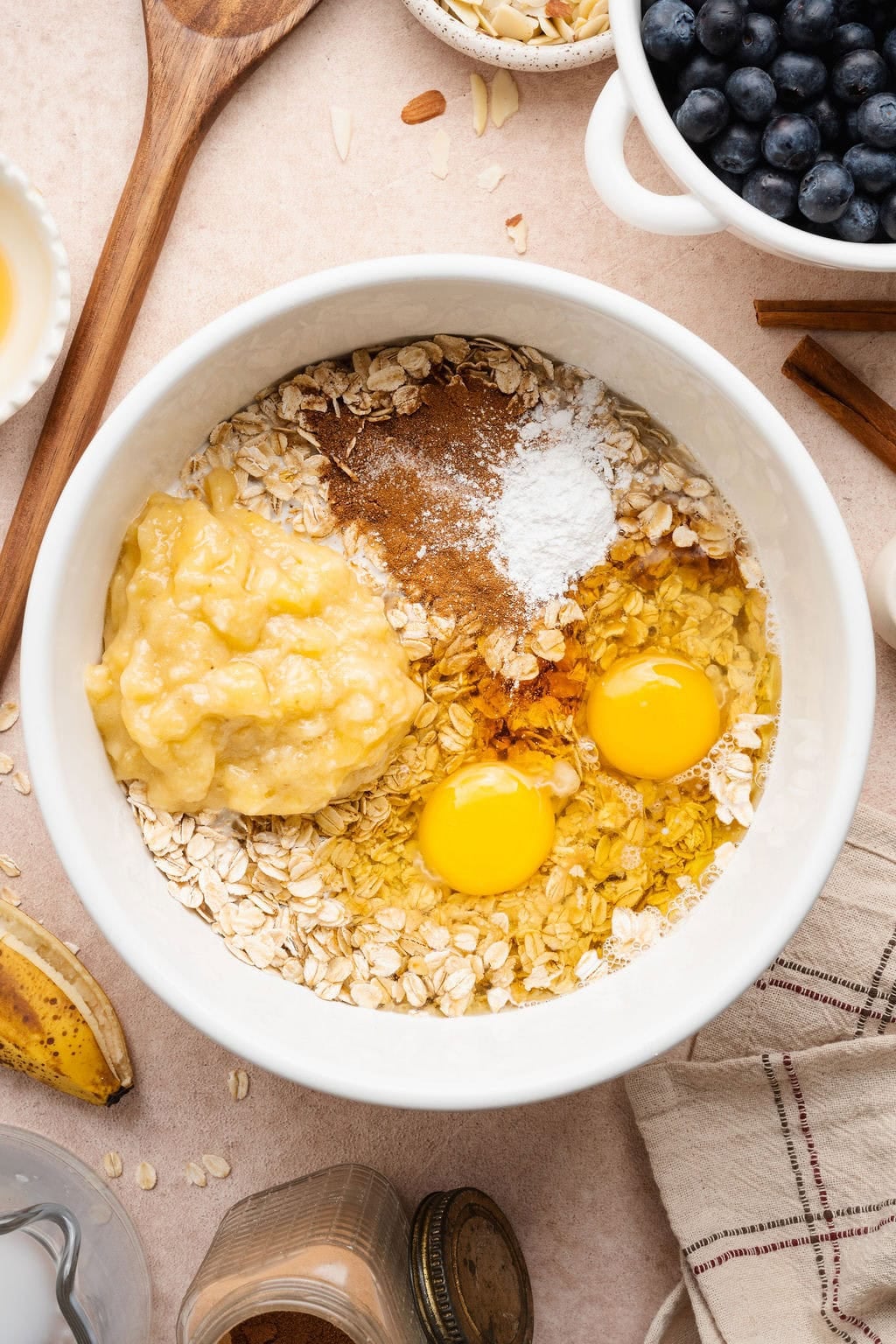 Overhead view of a bowl filled with oatmeal, eggs, and spices ready for stirring.